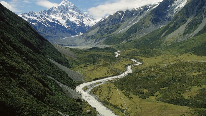 Winding river through a valley with snow-capped mountains
