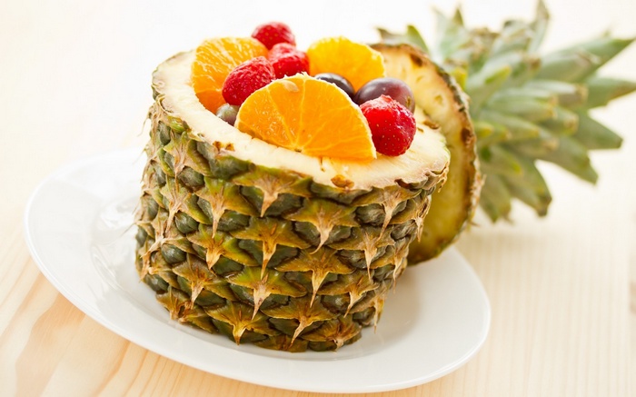 Pineapple fruit bowl with oranges, raspberries, and grapes
