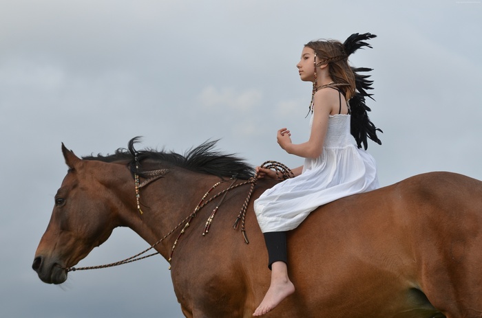 Girl with feathers riding a brown horse
