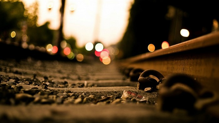 Railway tracks at dusk with bokeh lights