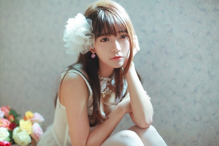 Yurisa Chan wearing a white dress with a flower accessory