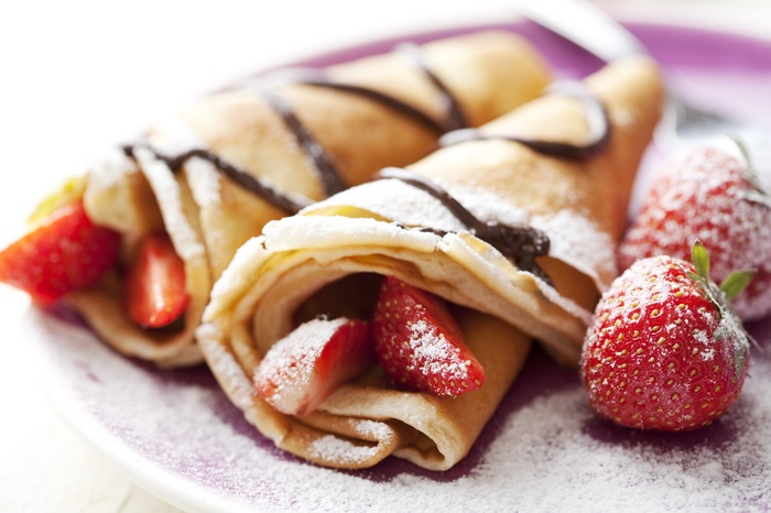 Chocolate drizzled crepes with strawberries and powdered sugar