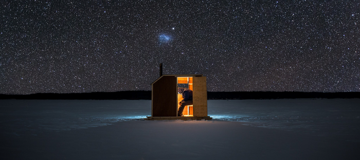 Person in illuminated hut under starry night sky