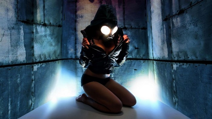 Woman in gas mask and hoodie kneeling