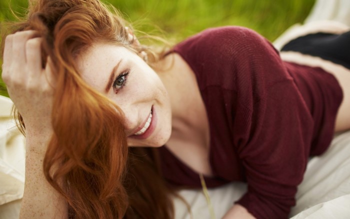Smiling Redhead Woman Lying Outdoors
