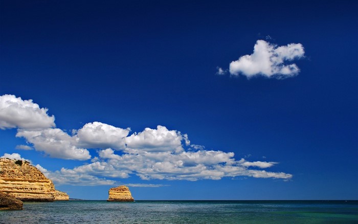 Rocky coast and sea under a blue sky with clouds