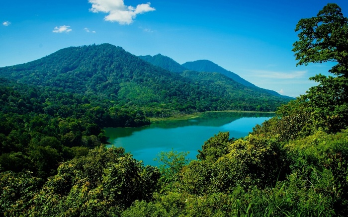 Turquoise lake surrounded by green mountains and trees