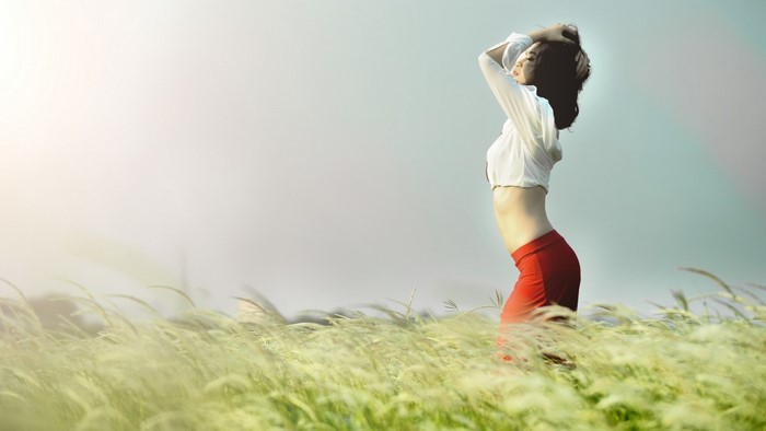 Woman in Red Skirt Standing in Sunlit Grass Field