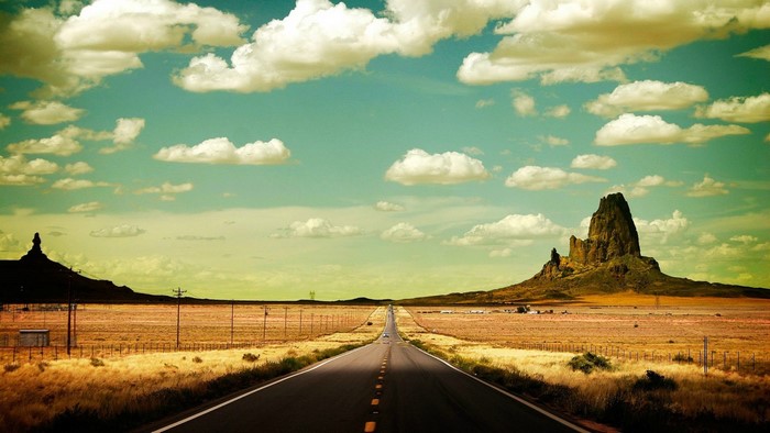 Desert highway with rock formations and clouds