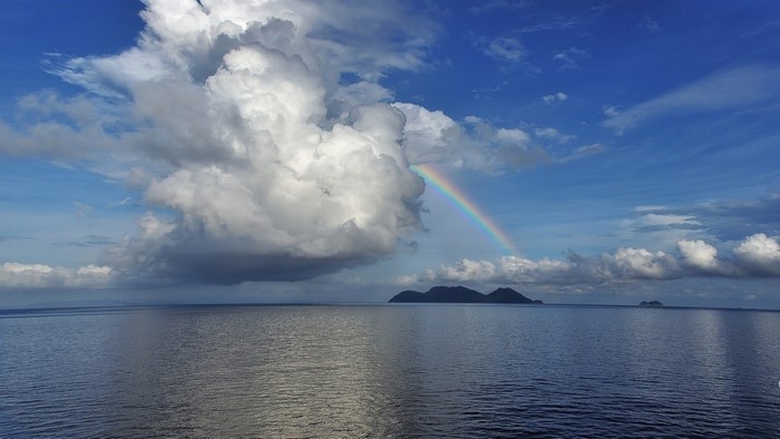 Rainbow over the ocean with islands and clouds