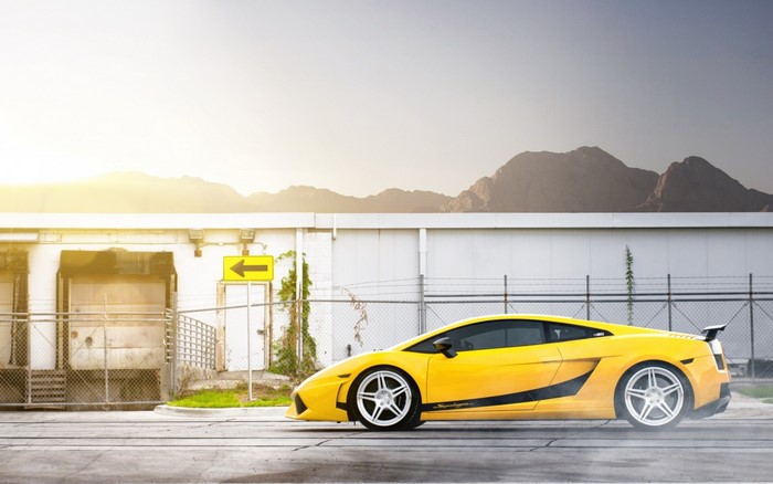 Yellow Lamborghini Gallardo parked near a warehouse