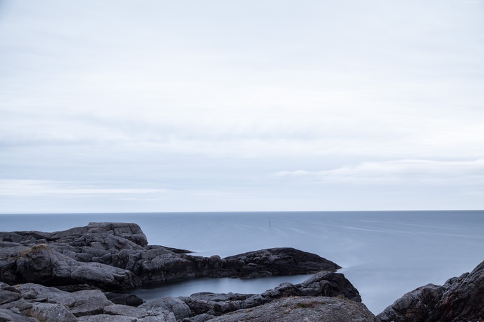 Rocky coastline overlooking a calm sea under a cloudy sky