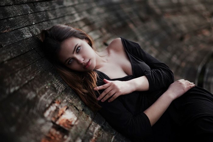 Elegant Woman in Black Dress Leaning on Wood