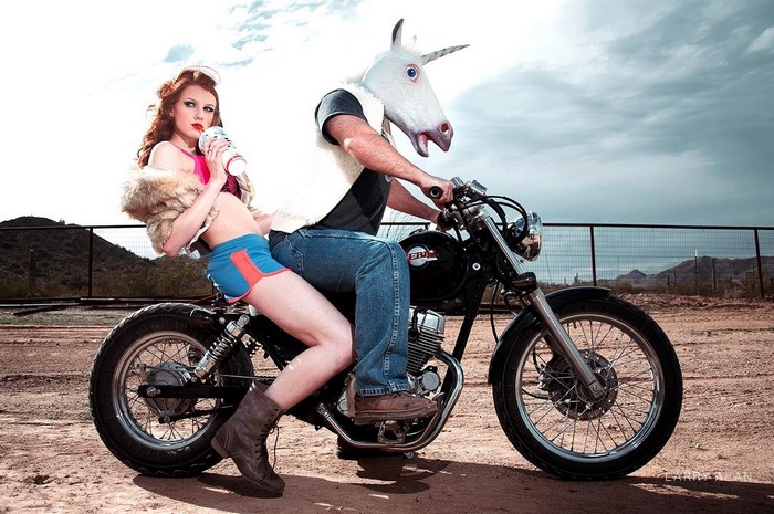 Woman and unicorn-headed person on a motorcycle