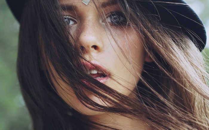 Close up portrait of a young woman with brown hair and a hat