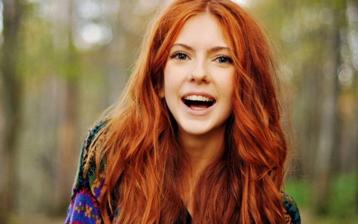 Woman with long red hair smiling outdoors
