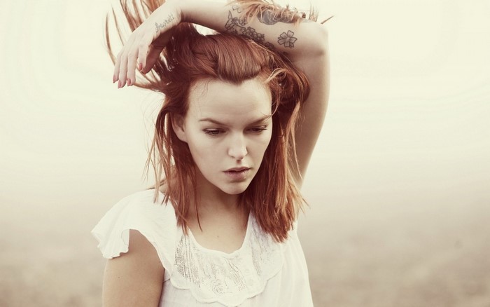 Woman with red hair and tattoos posing