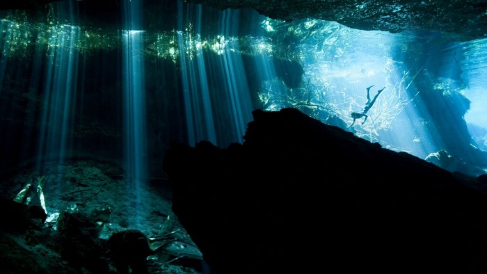 Underwater cave with sunbeams and a diver