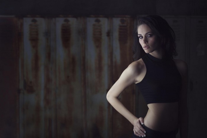 Woman in black crop top posing in front of lockers