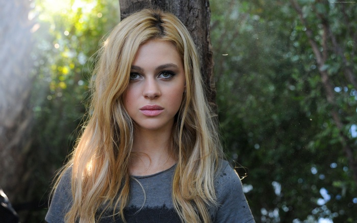 Nicola Peltz standing by a tree