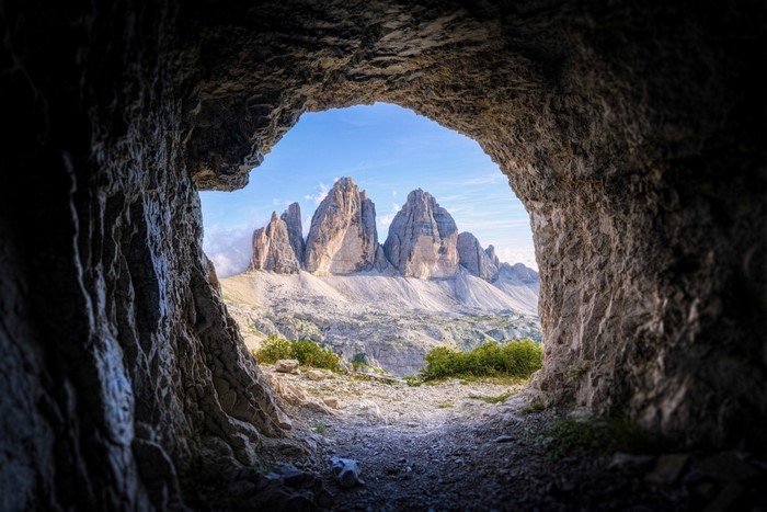 View of Tre Cime di Lavaredo mountains from a cave entrance