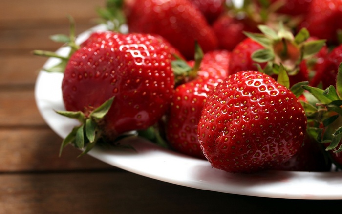 Plate of fresh strawberries on a wooden table