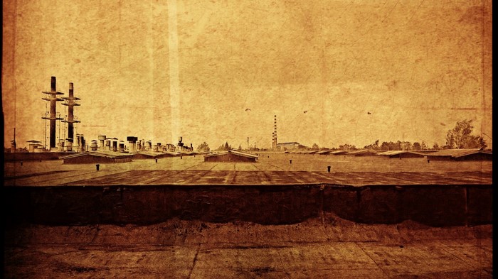 Sepia-toned industrial complex with rooftops and smokestacks