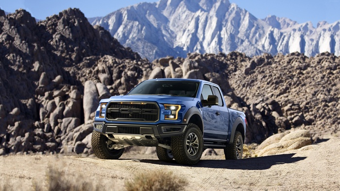 Blue Ford F-150 Raptor in a rocky desert landscape