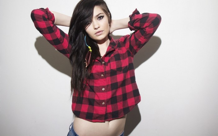 Woman in red and black plaid shirt with hands behind head