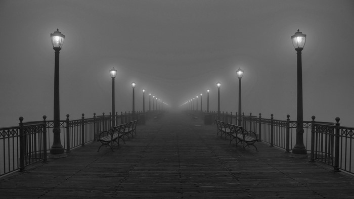 Pier with street lights and benches in fog