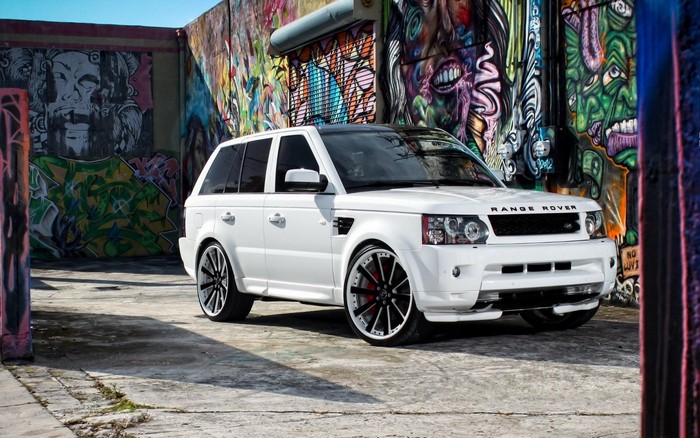 White Range Rover Sport parked in front of graffiti wall