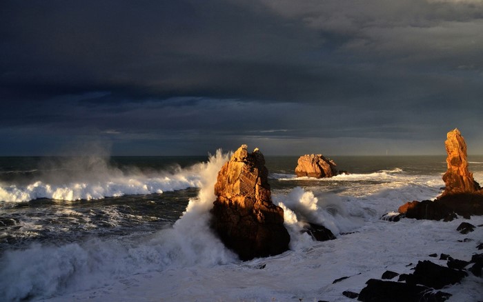 Waves crashing on rocks at sunset