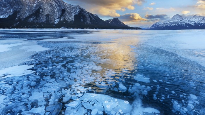 Frozen lake with ice bubbles and mountains