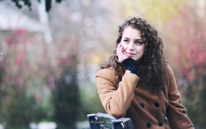 Young woman with curly hair in a brown coat