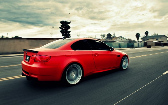 Red BMW M3 Coupe driving on a road