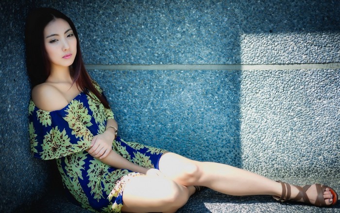 Elegant Woman Sitting in Floral Dress by Blue Wall