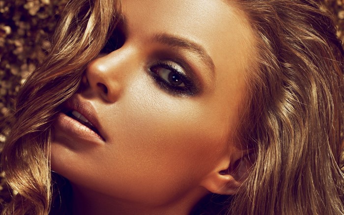 Close-up portrait of a woman with bronzed skin and makeup