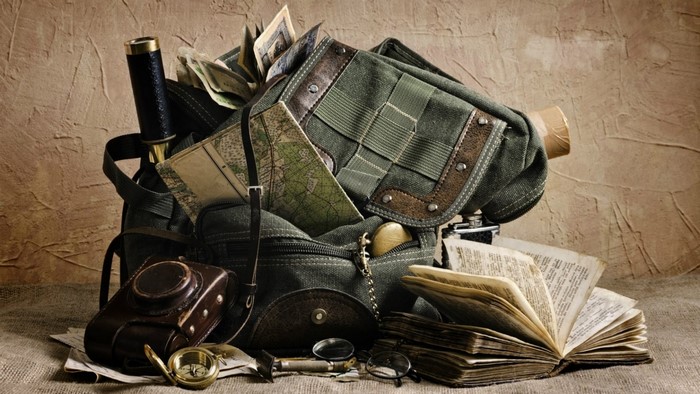 Adventurer's backpack with maps, books, and vintage camera