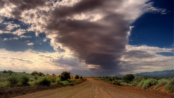 Dirt road through a landscape with dramatic clouds