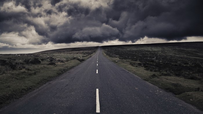Empty road stretching towards the horizon under stormy clouds