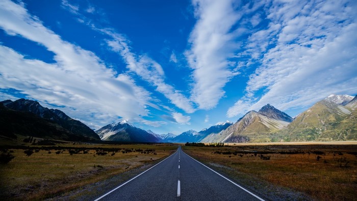 Scenic mountain road under a cloudy blue sky