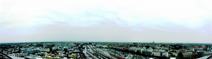 Panoramic cityscape with railway tracks and buildings under a cloudy sky