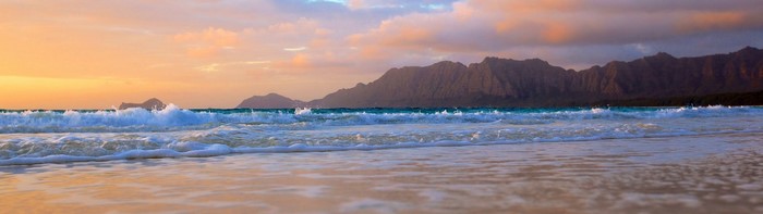Sunset over the ocean with waves and mountains