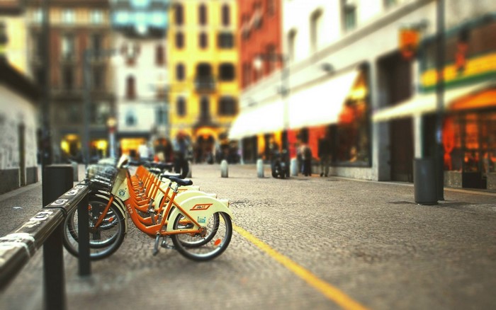 Row of rental bicycles parked on a cobblestone street in a city