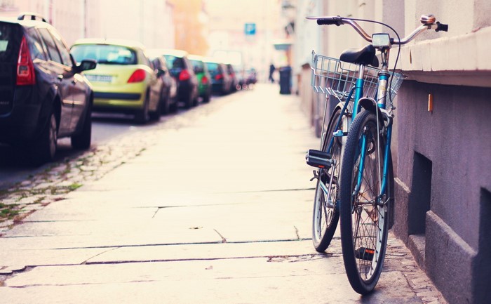 Blue bicycle parked on a city street next to parked cars