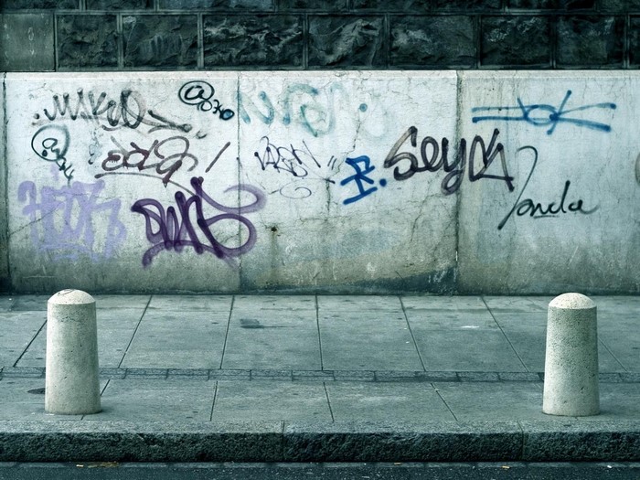 Graffiti on a concrete wall with bollards