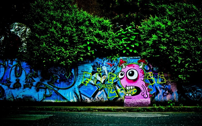 Graffiti monster on a wall with trees at night