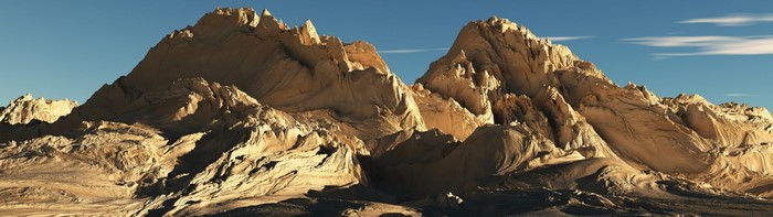 Sunlit mountain range with rugged terrain under a blue sky