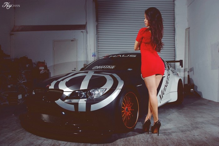 Asian woman in red dress posing with a custom sports car