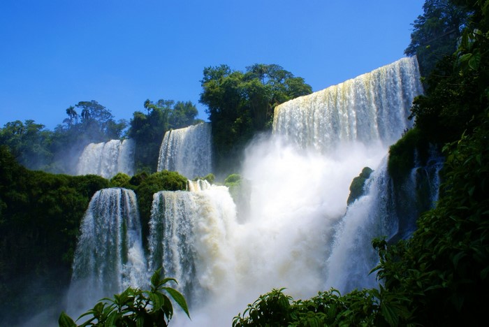 Iguazu Falls in a lush rainforest under a clear blue sky